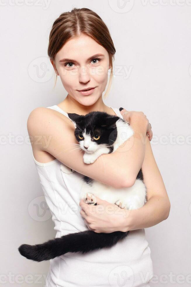 Beautiful smiling woman with a kitten in her arms, studio picture, close-up photo