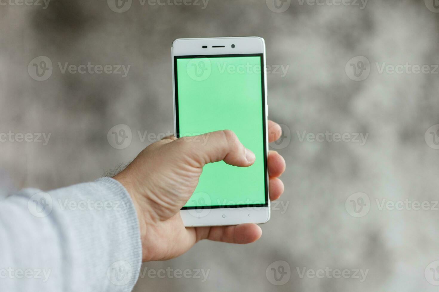 Closeup man hand holding and touching phone with green screen vertical photo