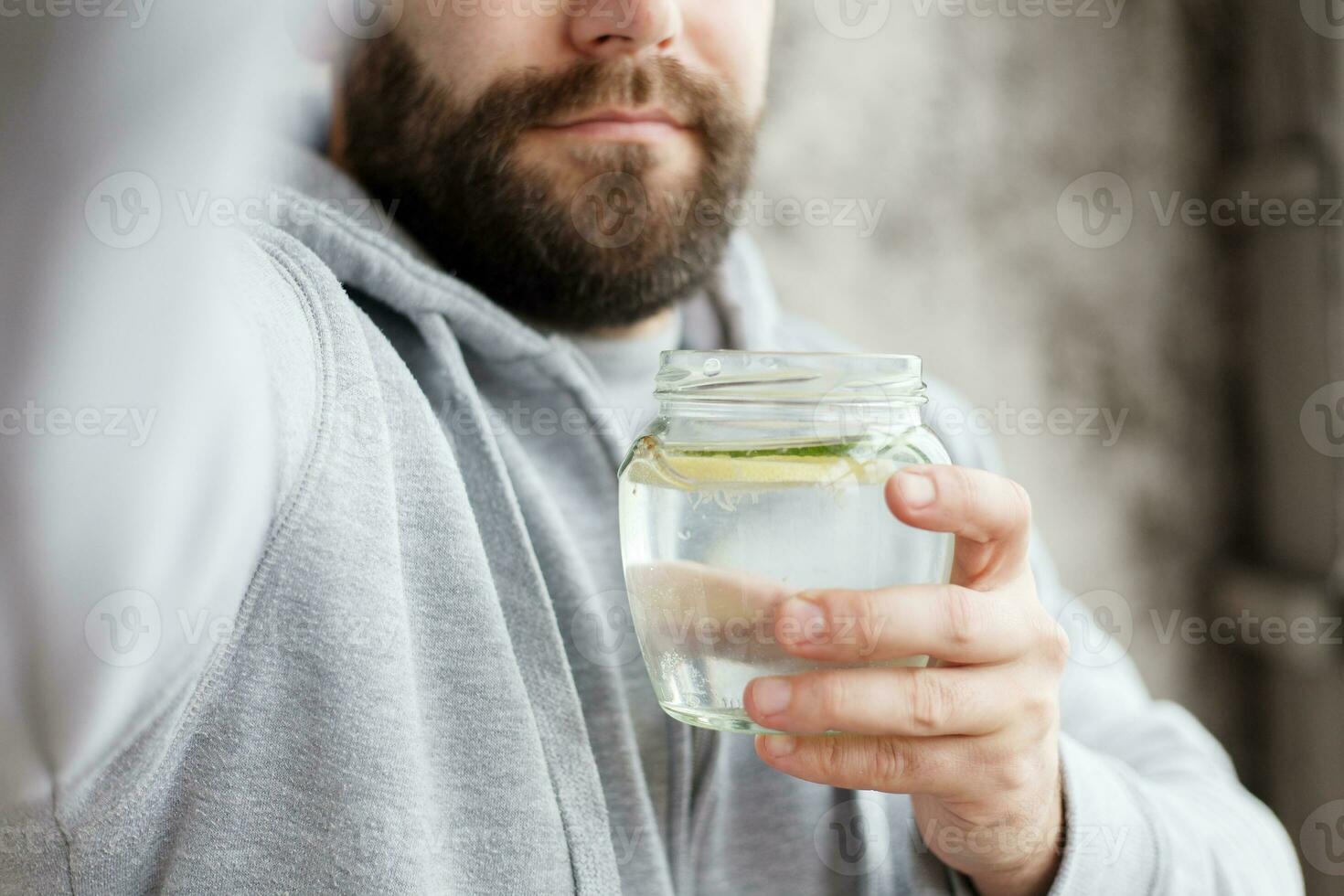 Handheld shot of a hooded man drinking water, in slow motion photo