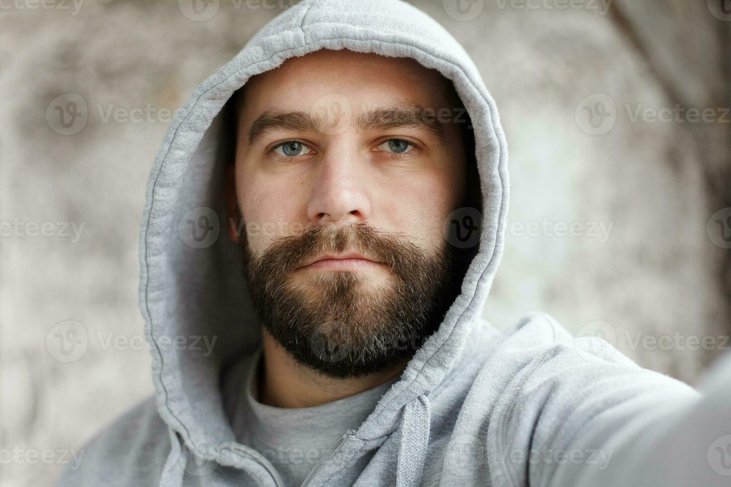 bearded man on a gray background makes a selfi photo