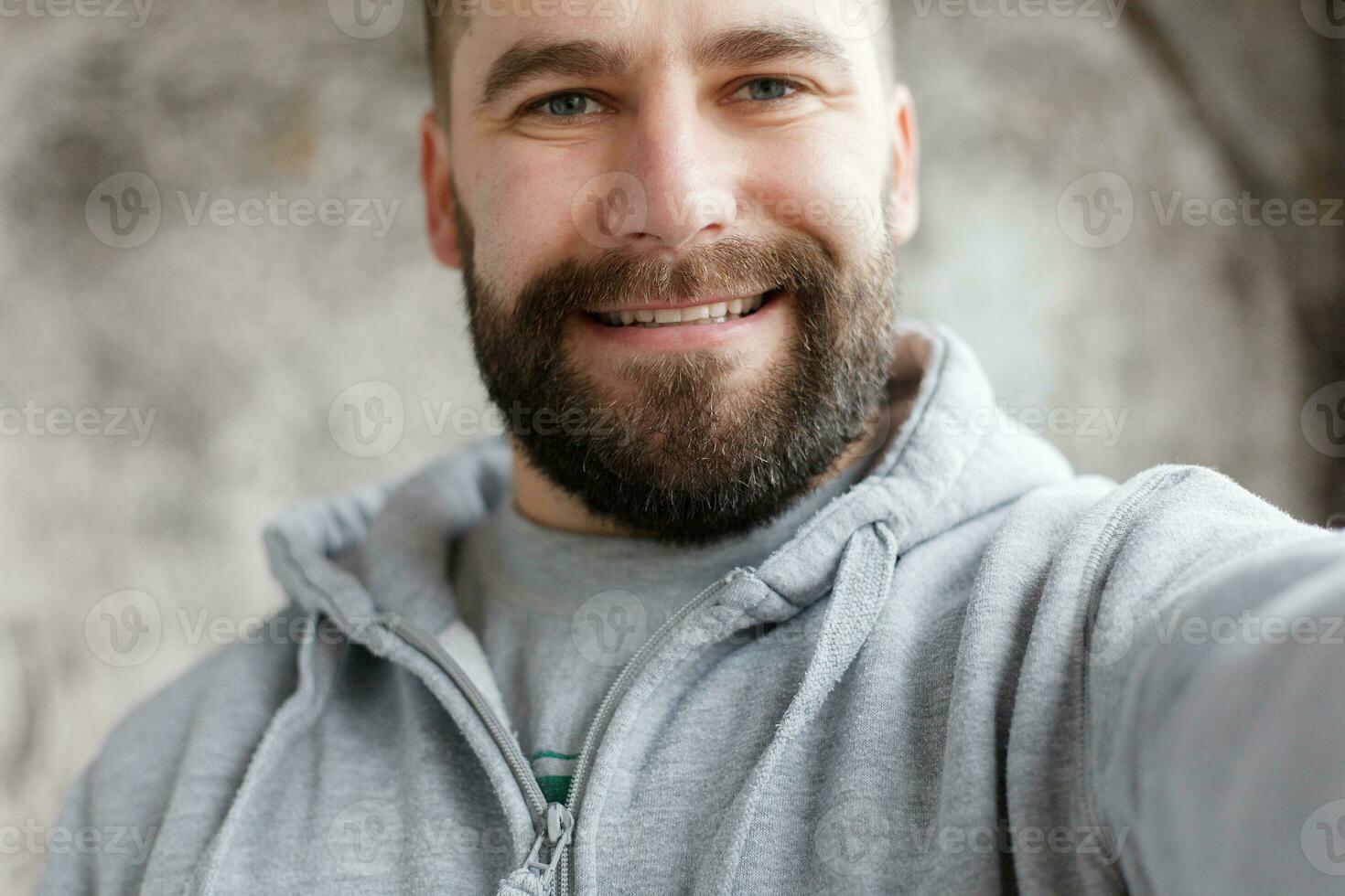 bearded man on a gray background makes a selfi photo