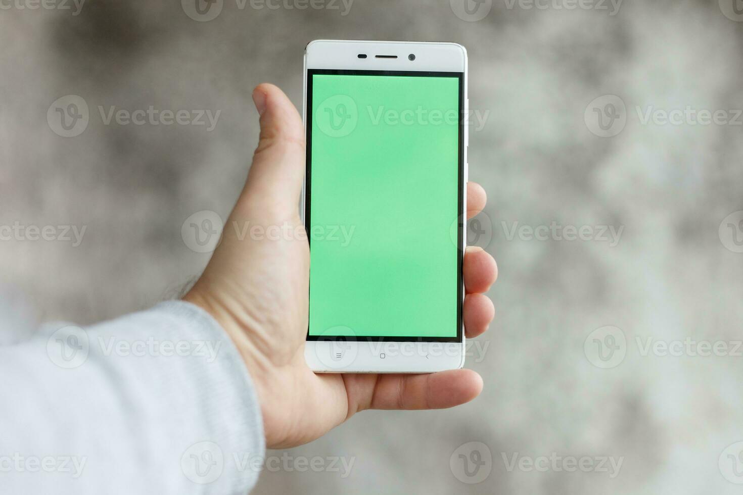 Closeup man hand holding and touching phone with green screen vertical photo