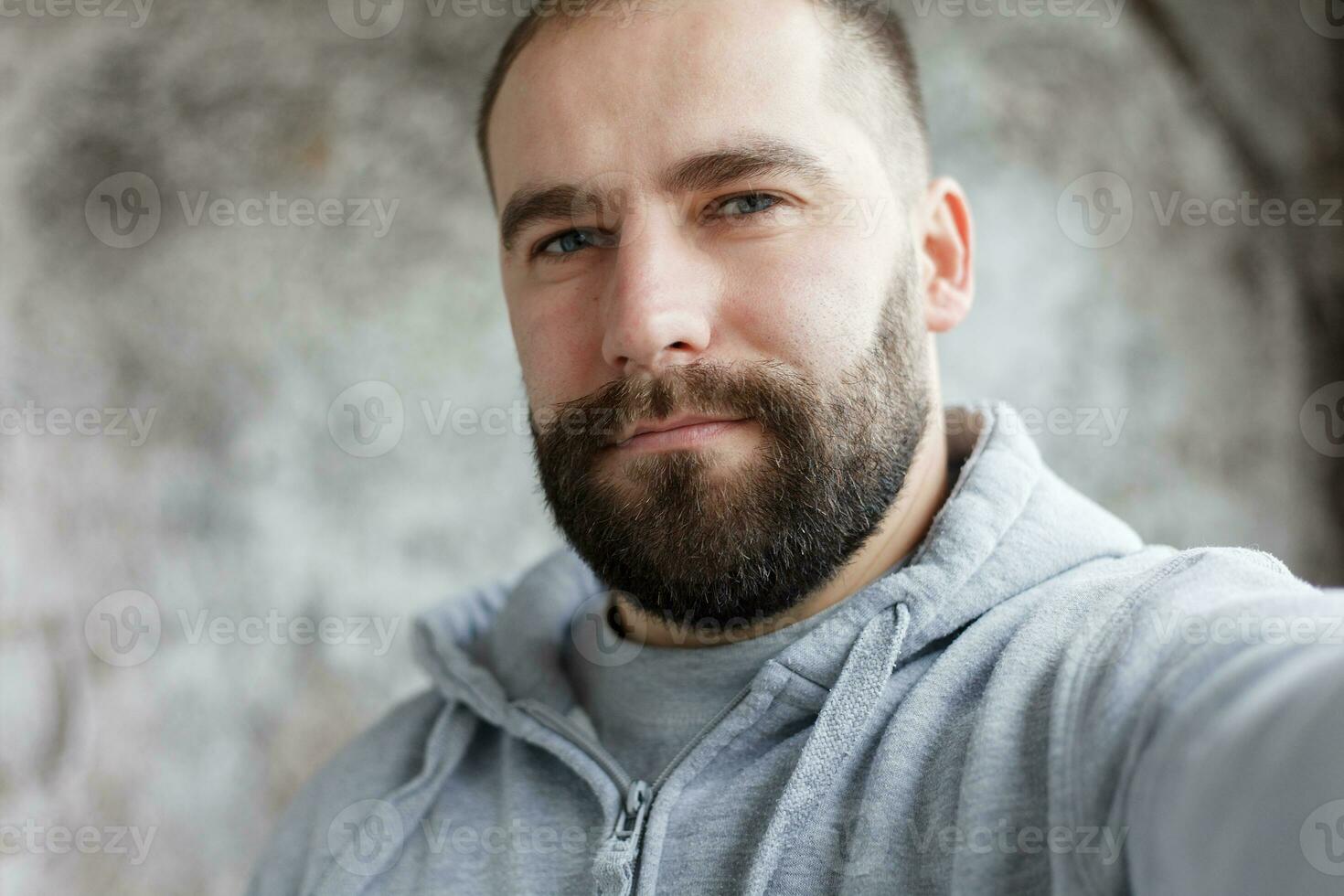 bearded man on a gray background makes a selfi photo