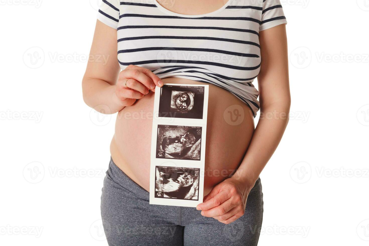 Pregnant woman standing and holding her ultrasound baby scan photo