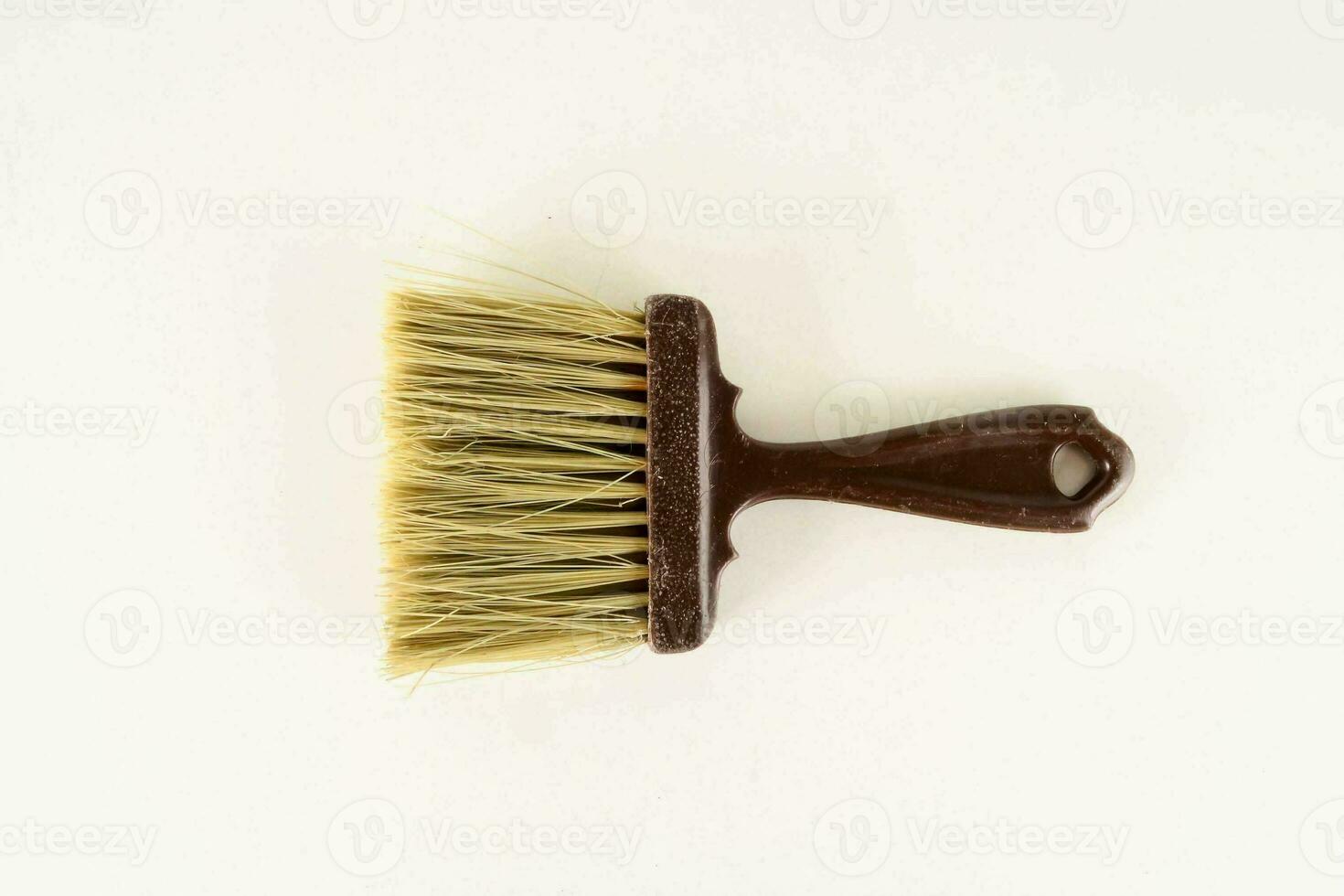 a brush with a wooden handle on a white surface photo