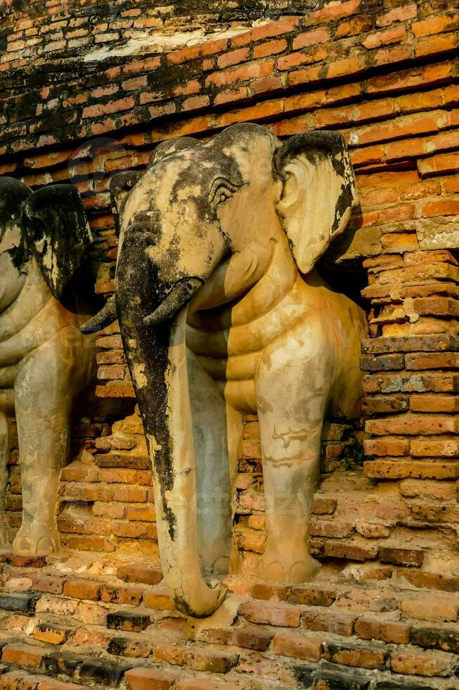 an elephant statue is sitting on a brick wall photo