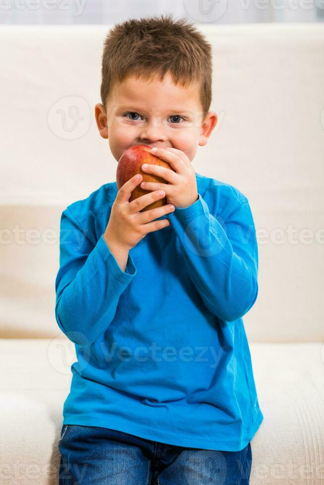 Cute little boy is eating apple. photo