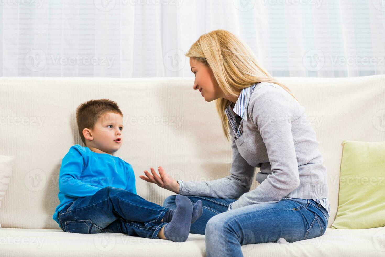 Mother and son sitting on sofa and talking about something. photo