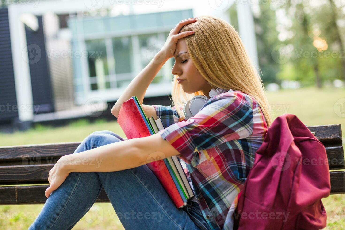 Exhausted and worried female student studying outdoor. photo