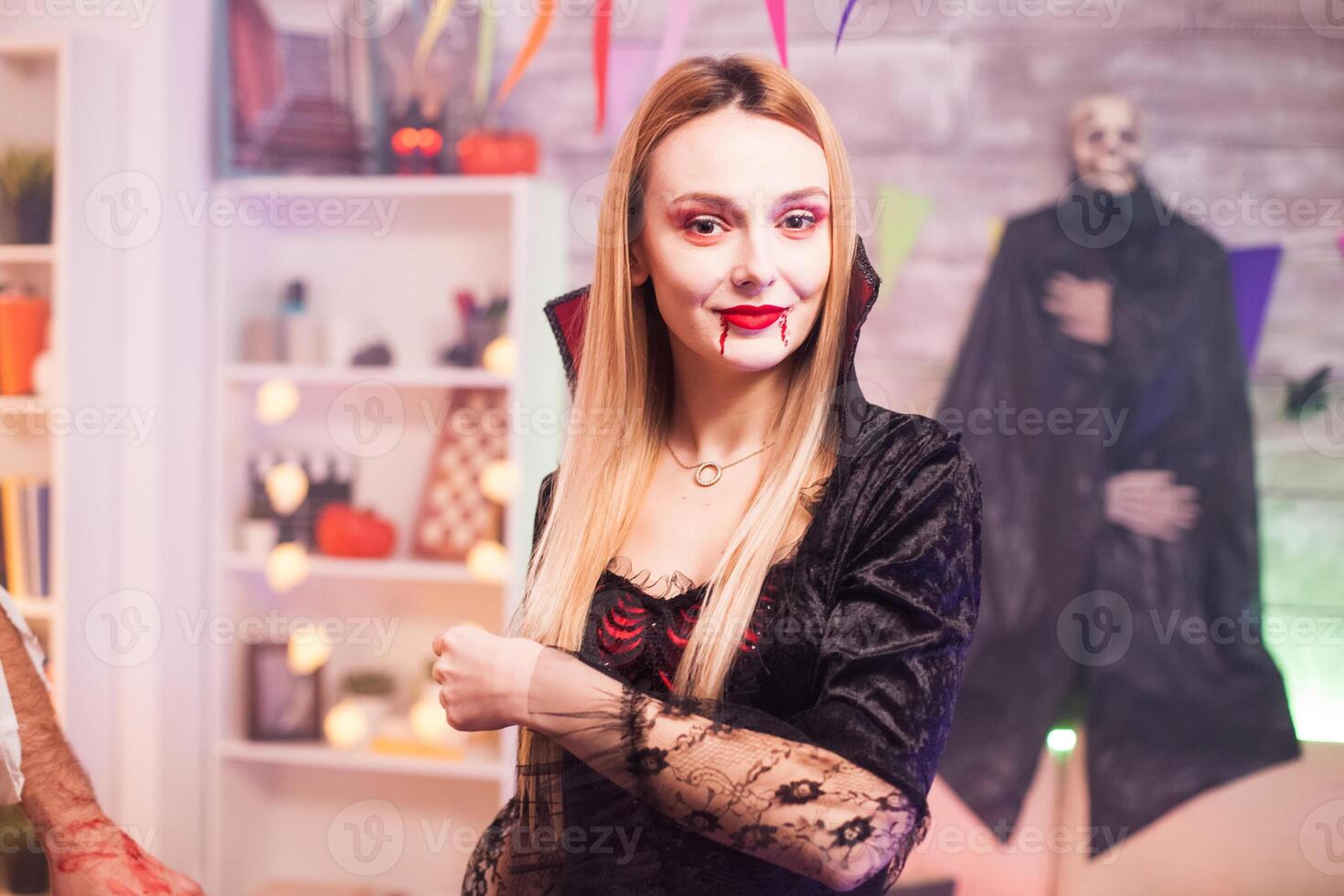 Portrait of beautiful woman dressed up like a vampire looking at the camera while celebrating halloween. photo