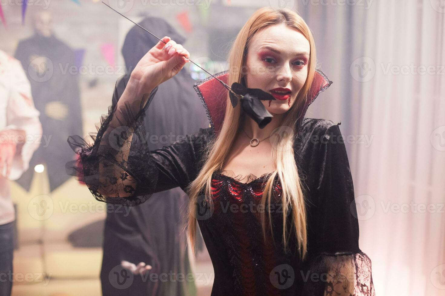 joven mujer vestido arriba me gusta un Siniestro vampiro con grupo de personas celebrando Víspera de Todos los Santos. foto