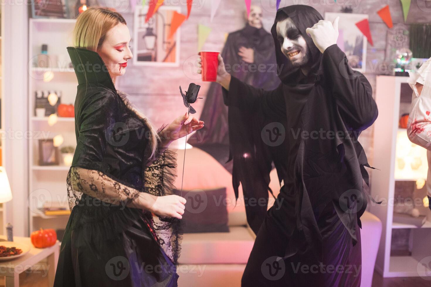 Grim reaper and beautiful vampire woman having fun at halloween party. photo