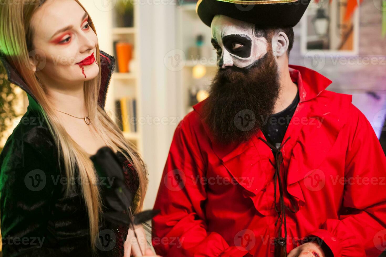 Man dressed up like a pirate trying to seduce vampire woman at halloween party. photo