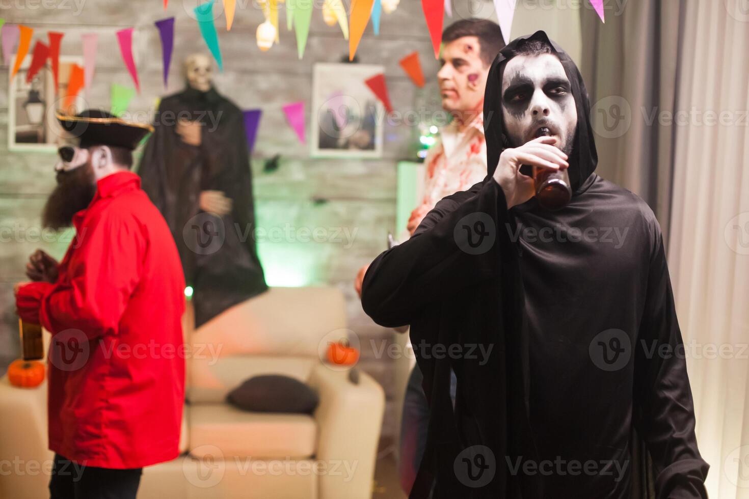 Grim reaper enjoying his beer at halloween celebration. Scary man. photo