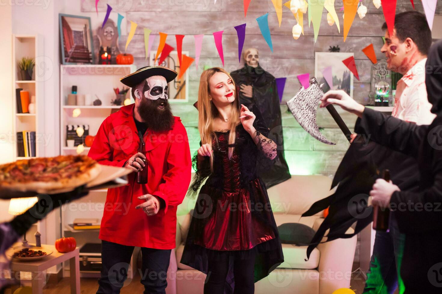 Young woman dressed up like a witch for halloween arriving with pizza at the party. photo