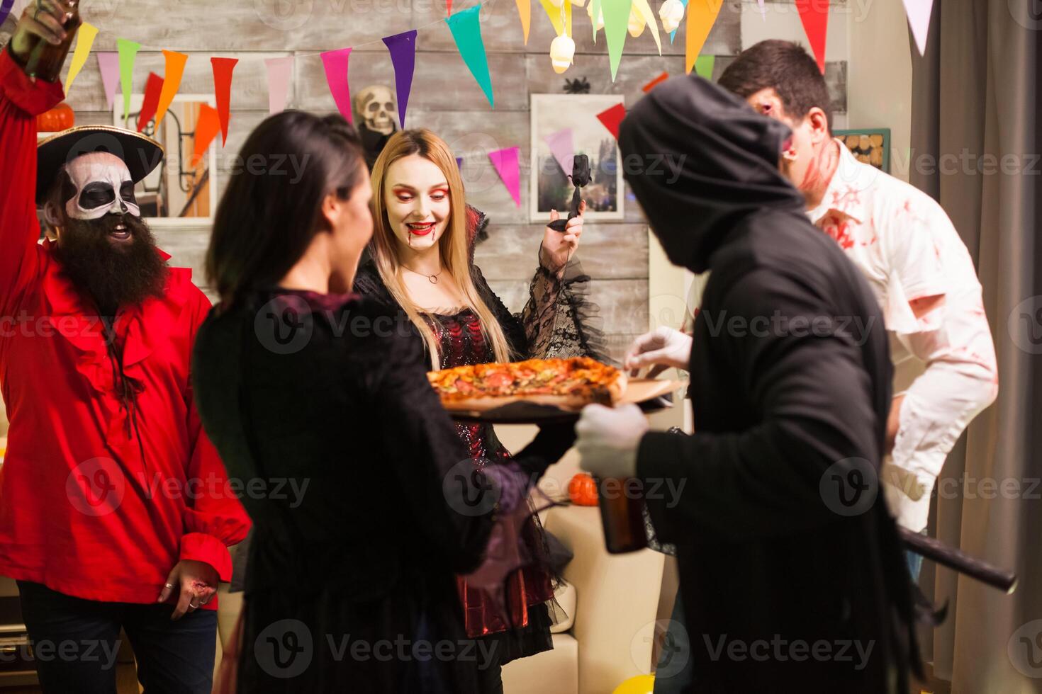 Group of friends excited about delicious pizza at halloween party. photo