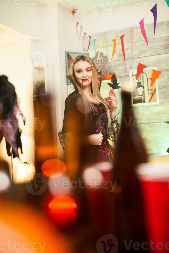 Portrait of beautiful vampire woman with bloody lips at halloween celebration. photo