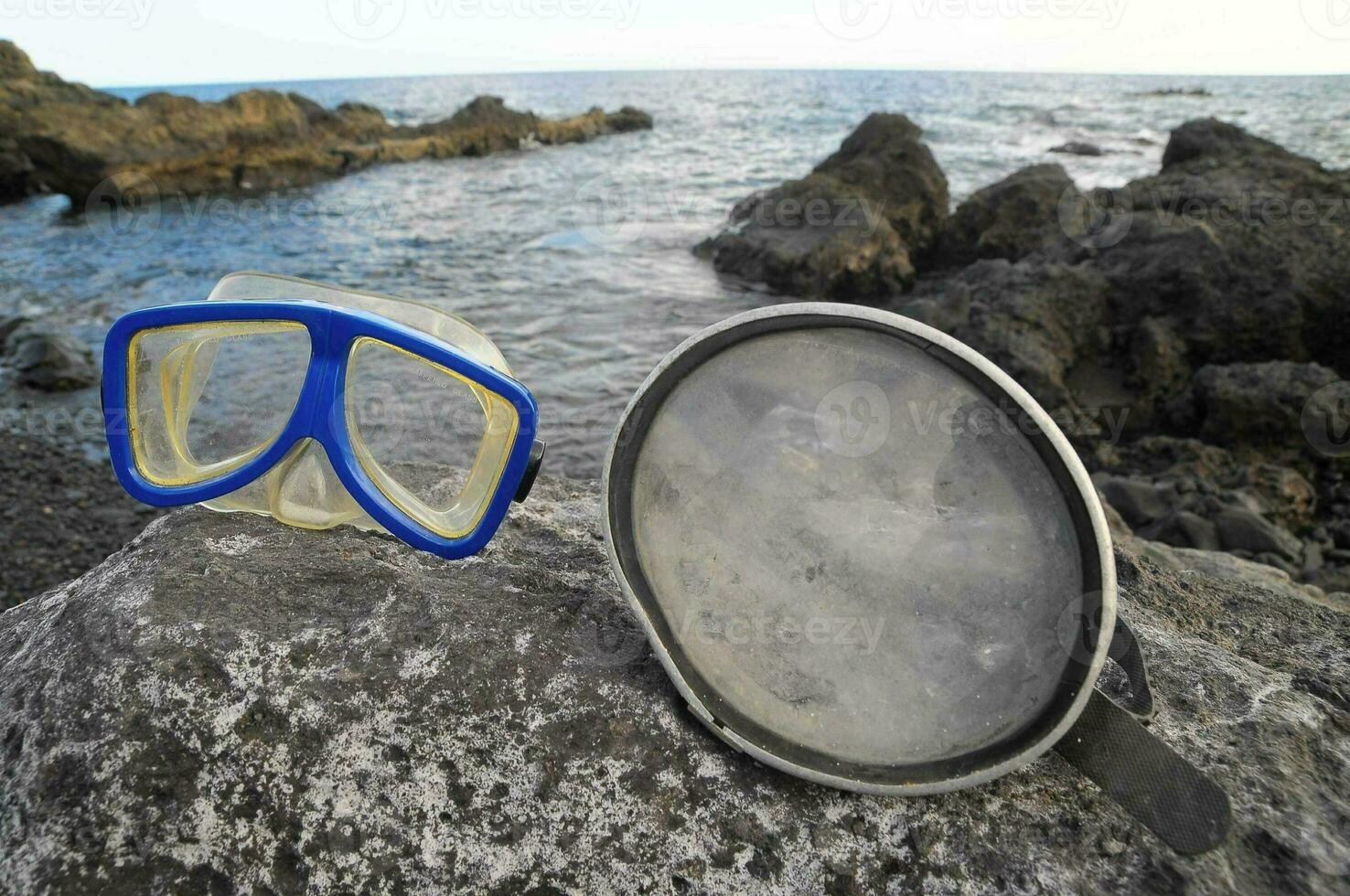 two diving masks and a snorkel on a rock photo