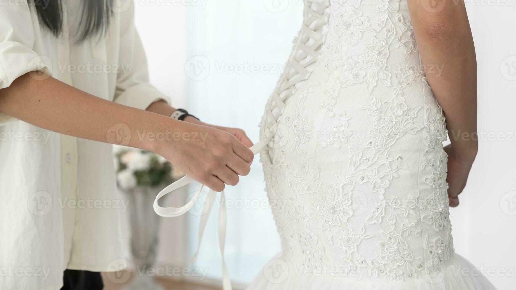 Close up of tying bow on elegant White bridal wedding dress photo