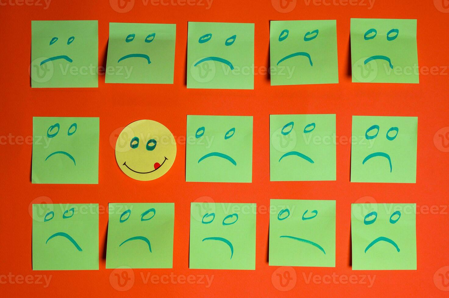 Concept for a positive attitude with small office notes with multiple faces and one stands out with a smile photo