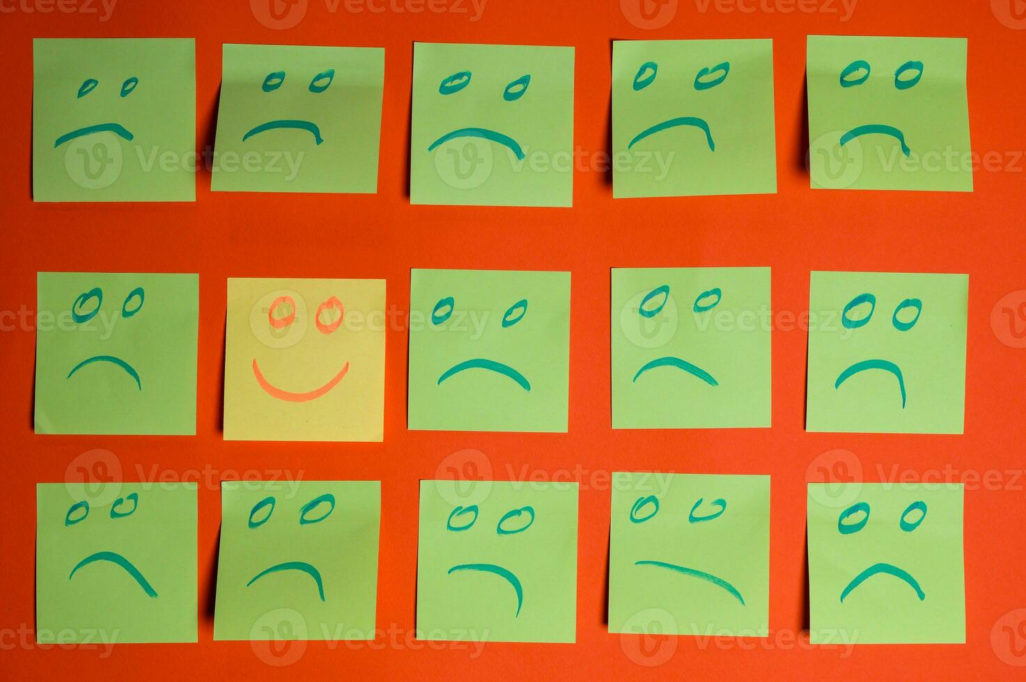 Concept for a positive attitude with small office notes with multiple faces and one stands out with a smile photo