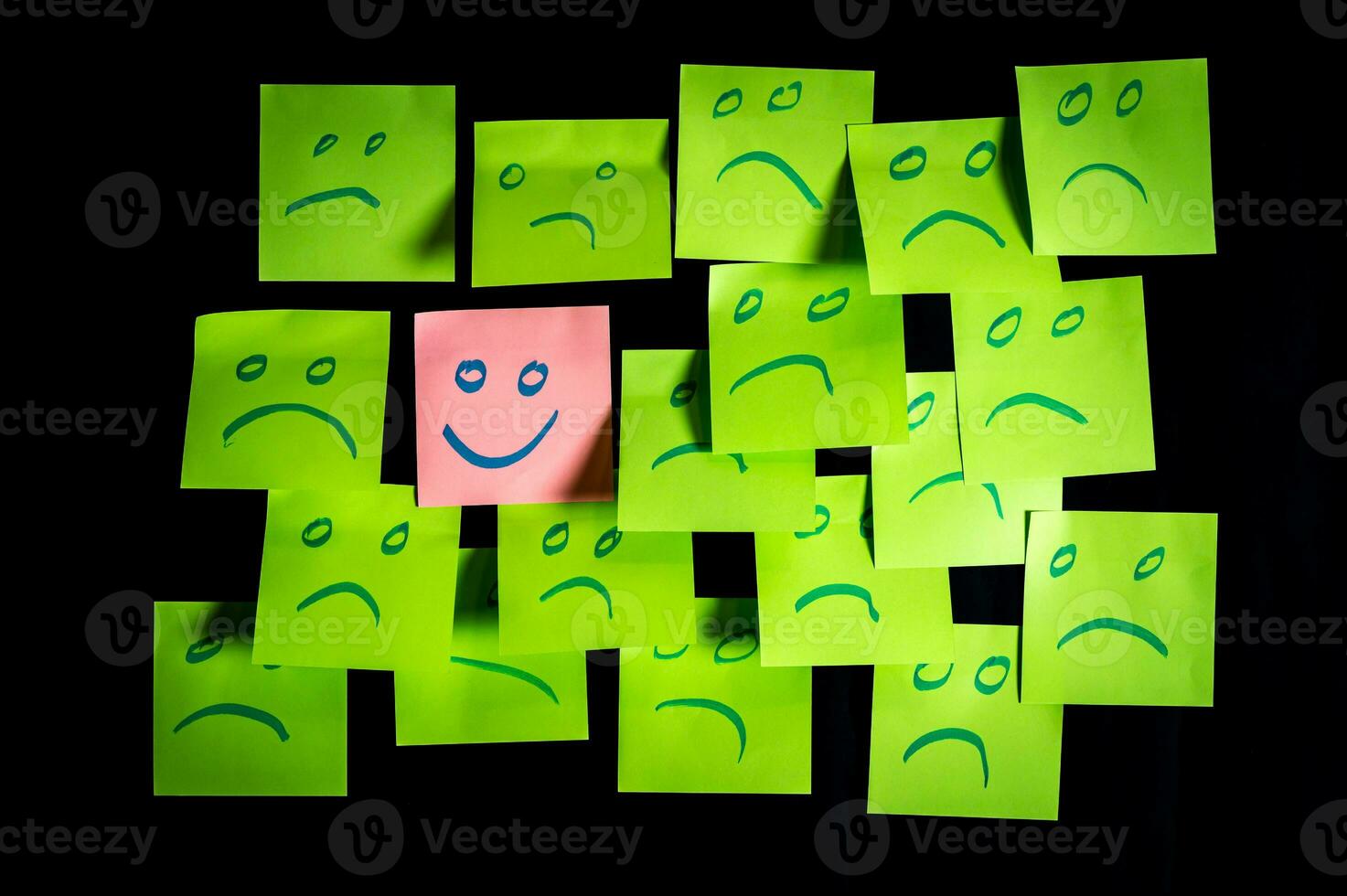 Concept for a positive attitude with small office notes with multiple faces and one stands out with a smile photo