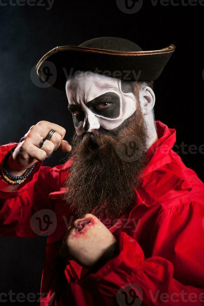 Medieval bearded man with pirate costume for halloween over black background. photo