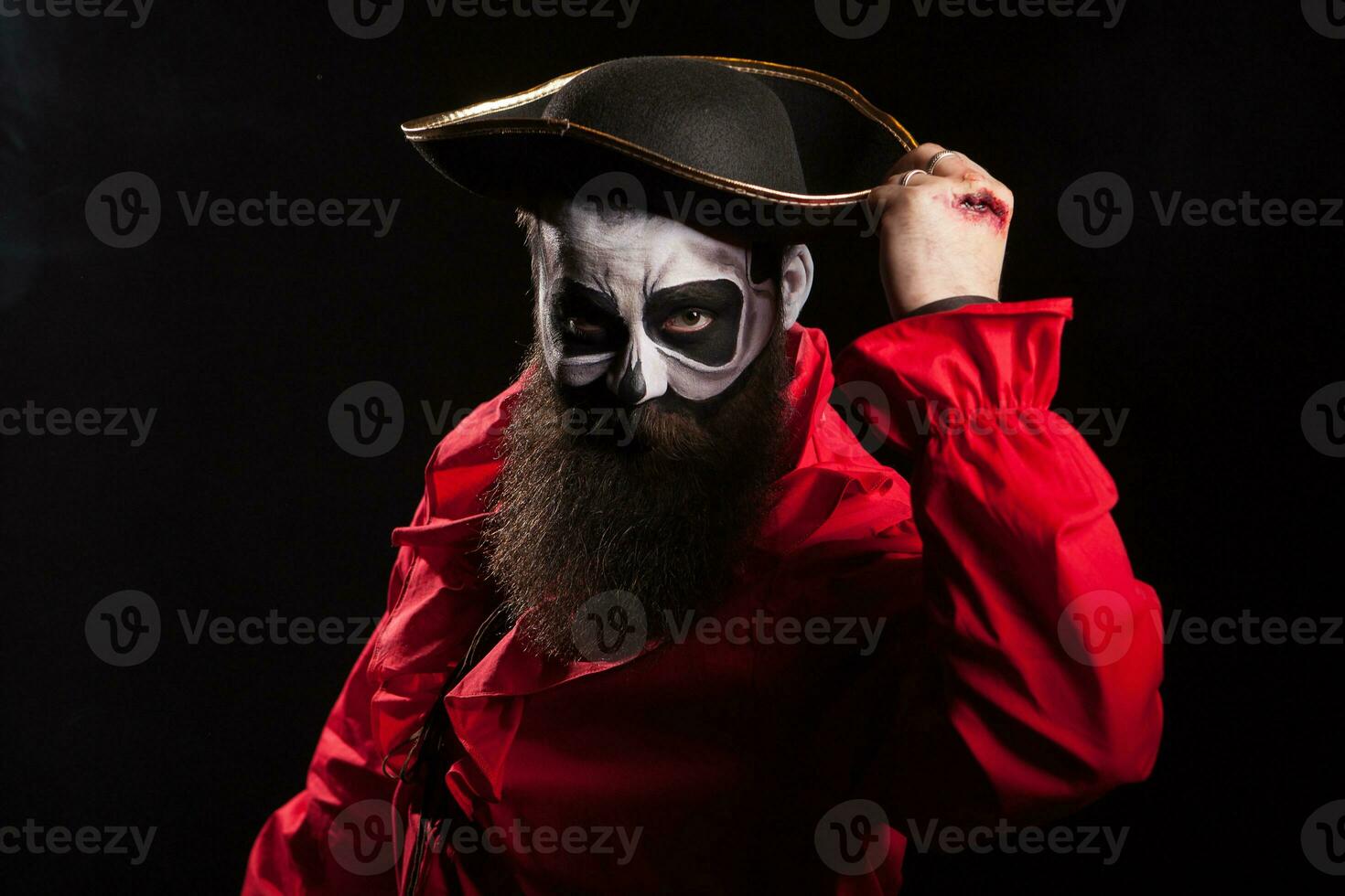 Bearded and spooky medieval pirate with blood on his hands over black background. Halloween disguise. photo