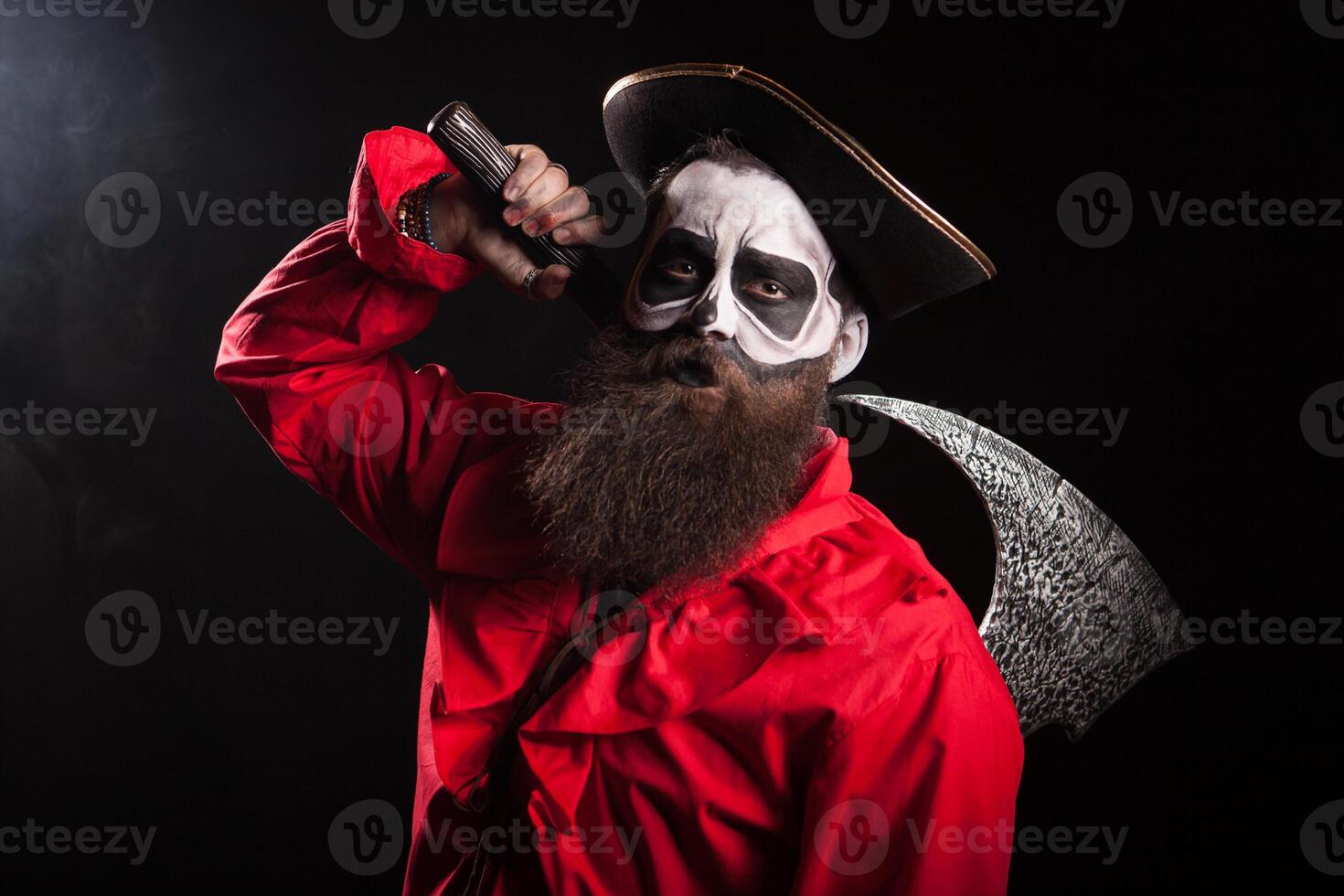 Crazy man dressed up like a medieval pirate with long beard and his axe for halloween over black background. photo