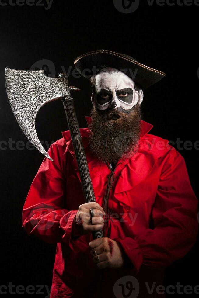 Bearded crazy pirate with his axe over black background. Halloween outfit. photo