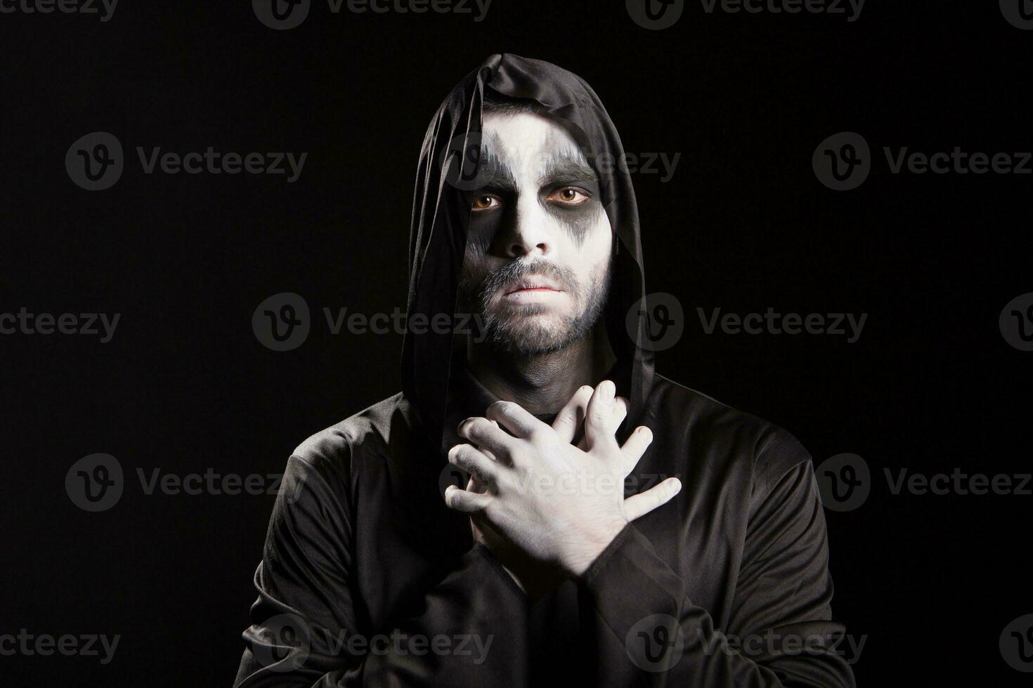 Spooky angel of death over black background with a hood. Halloween outfit. photo
