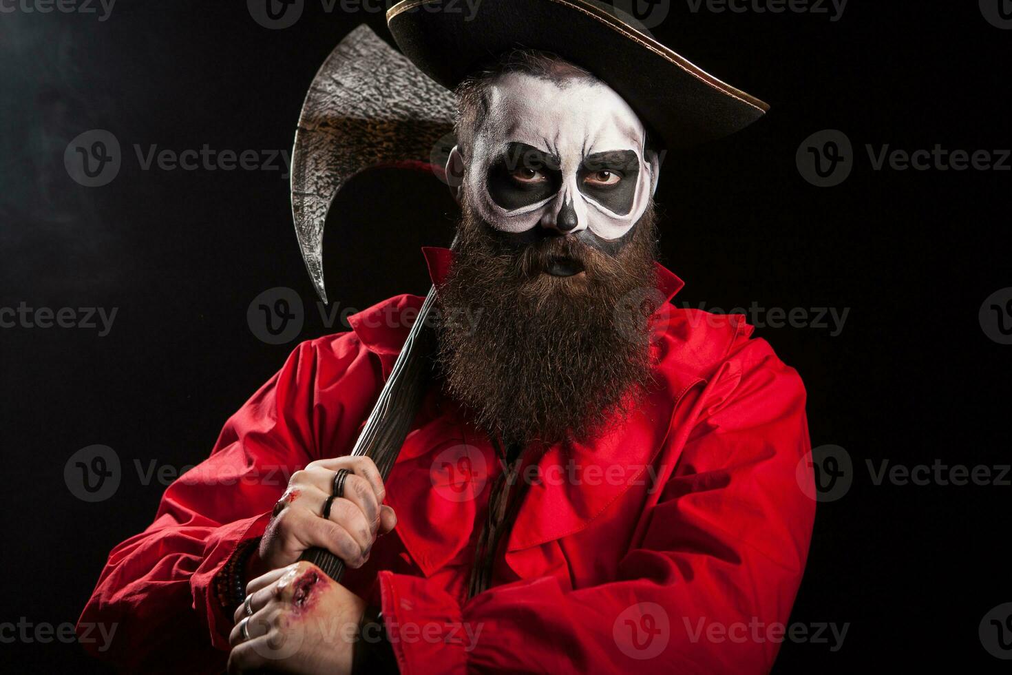 Medieval captain holding an axe over black background. Halloween outfit. photo