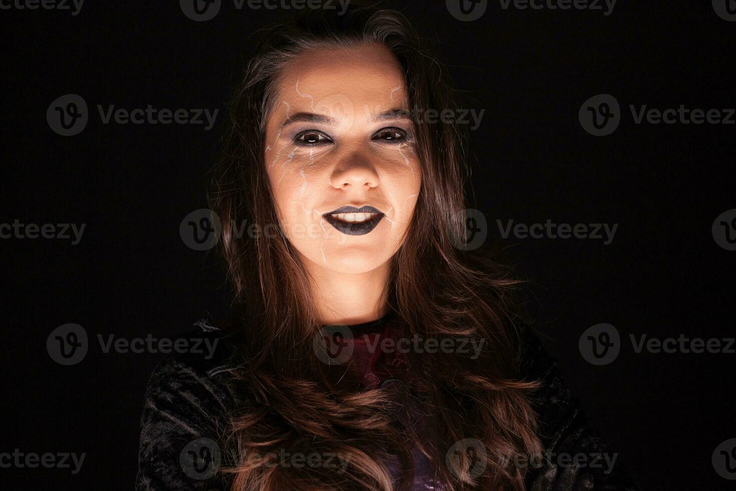 Attractive woman in a witch outfit for halloween looking at the camera over black background. photo