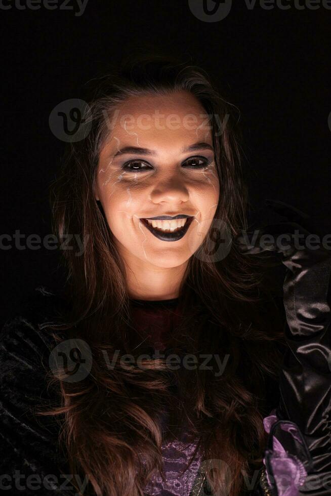 Beautiful woman over black background dressed up like a scary witch for halloween. photo