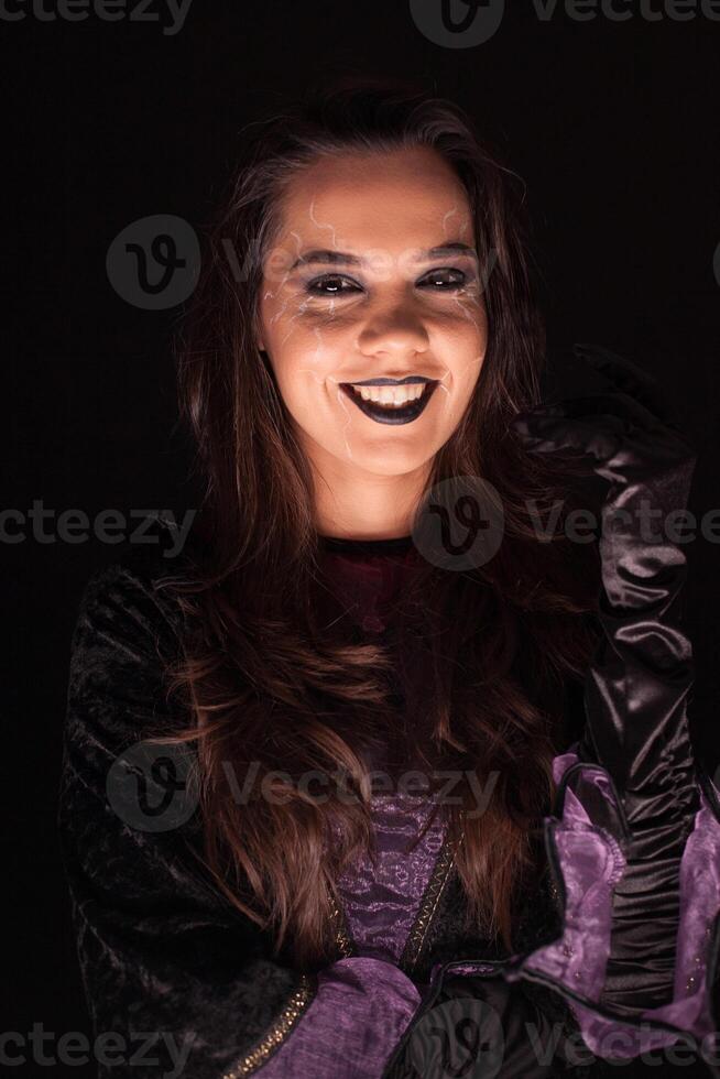 Young woman with a witch outfit for halloween over black background photo