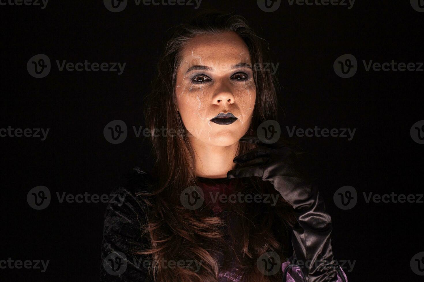 Lady wearing a witch costume over black background. Scary girl. Halloween outfit. photo