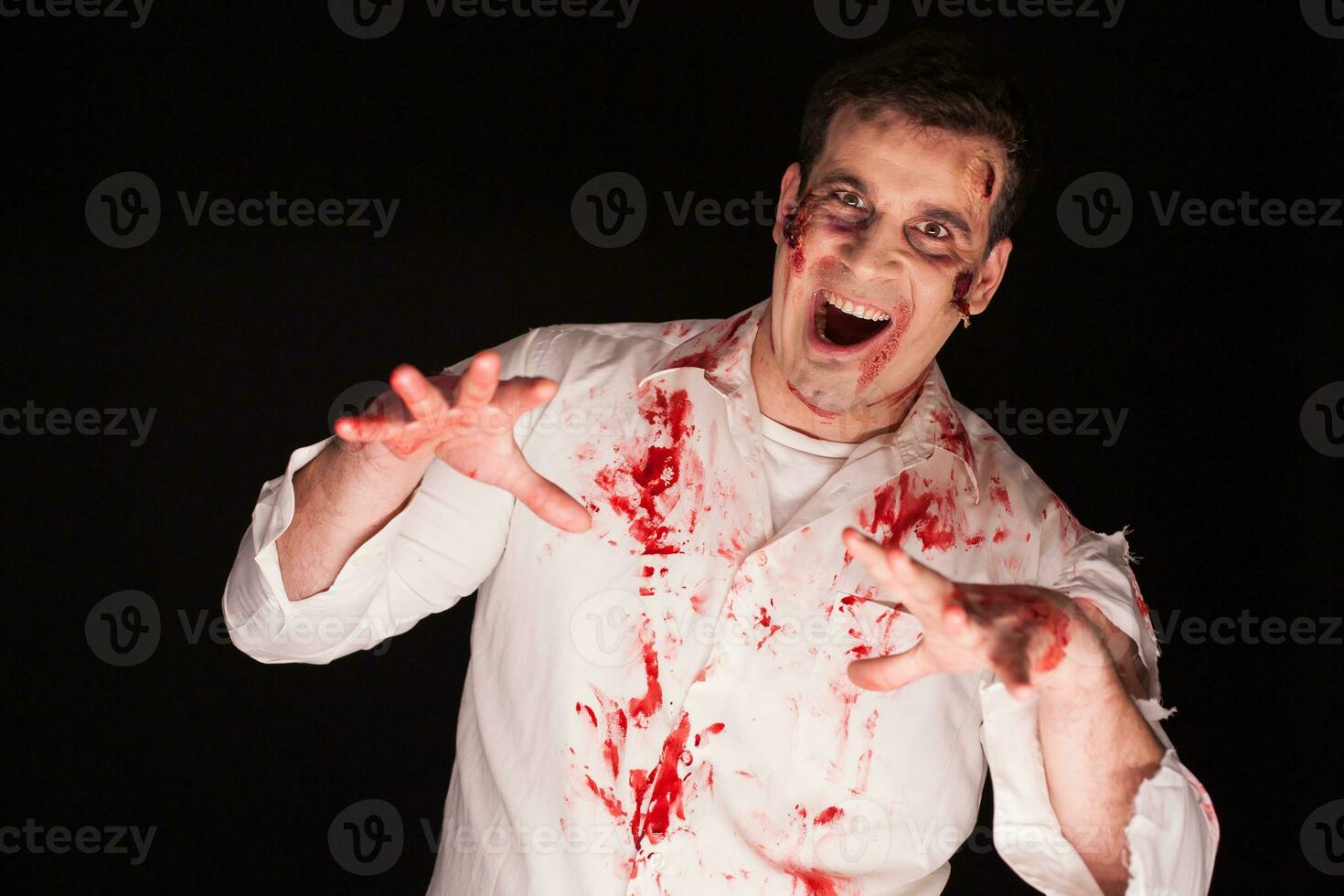 Person possessed by a zombie covered in blood over black background. Halloween costume. photo