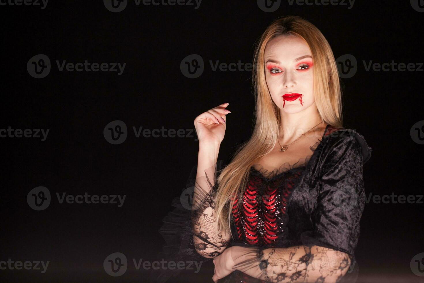 Lady of death with dripping blood from lips over black background. Halloween costume. photo