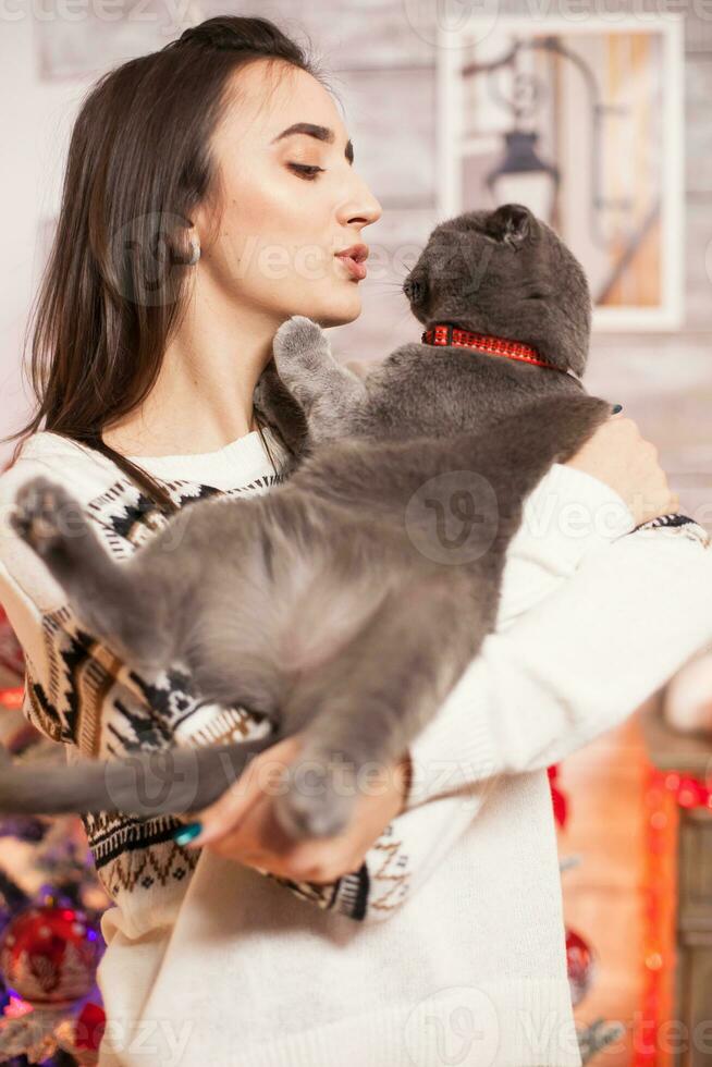 Cheerful young woman trying to kiss her cat on christmas day. photo