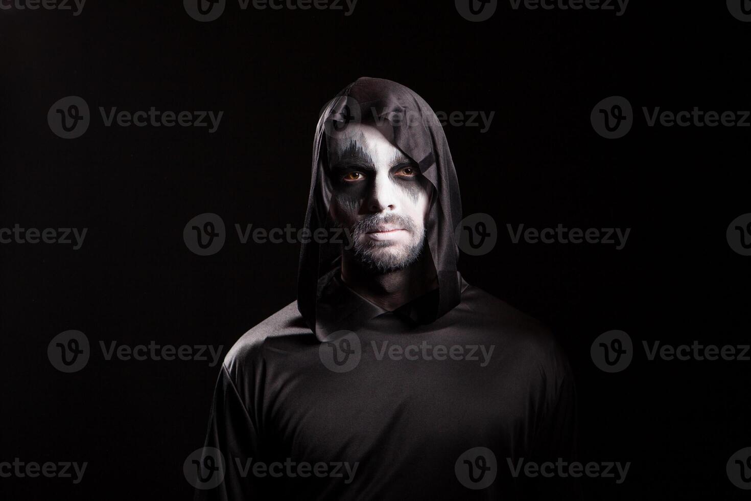 Portrait of man dressed up like angel of death over black background for halloween. photo