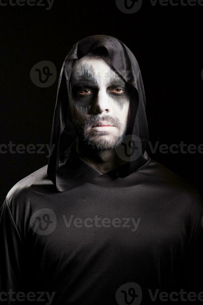 Grim reaper with a hood isolated over black background. Halloween costume. photo