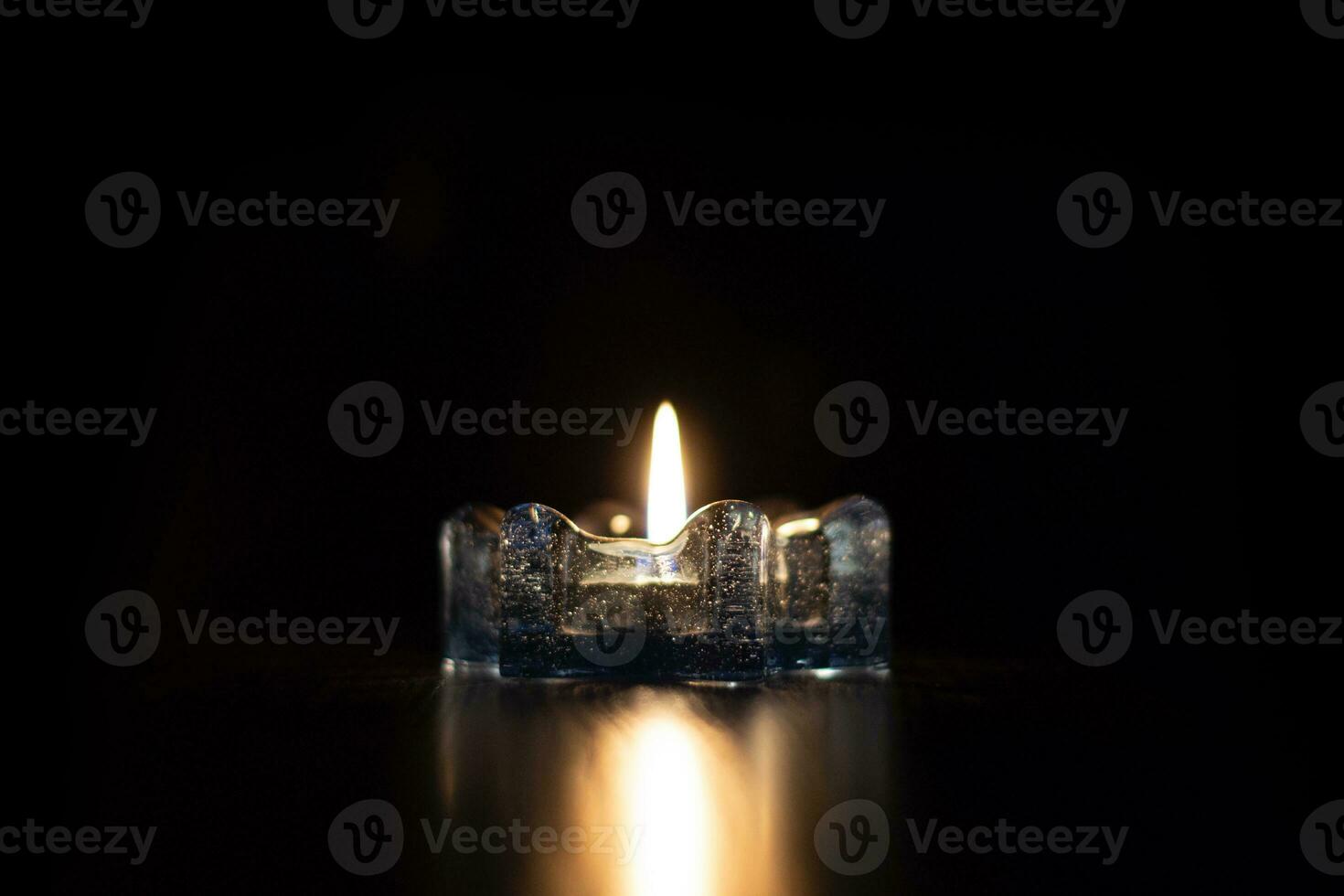 One candle light burning brightly in the black background in the ice candlestick. photo