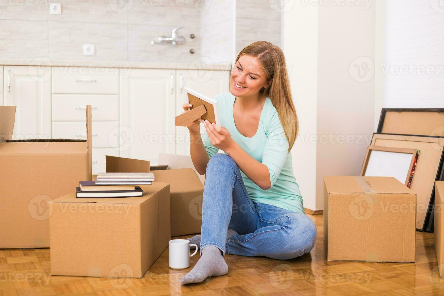 Beautiful woman looking at photo in frame while moving into new home.