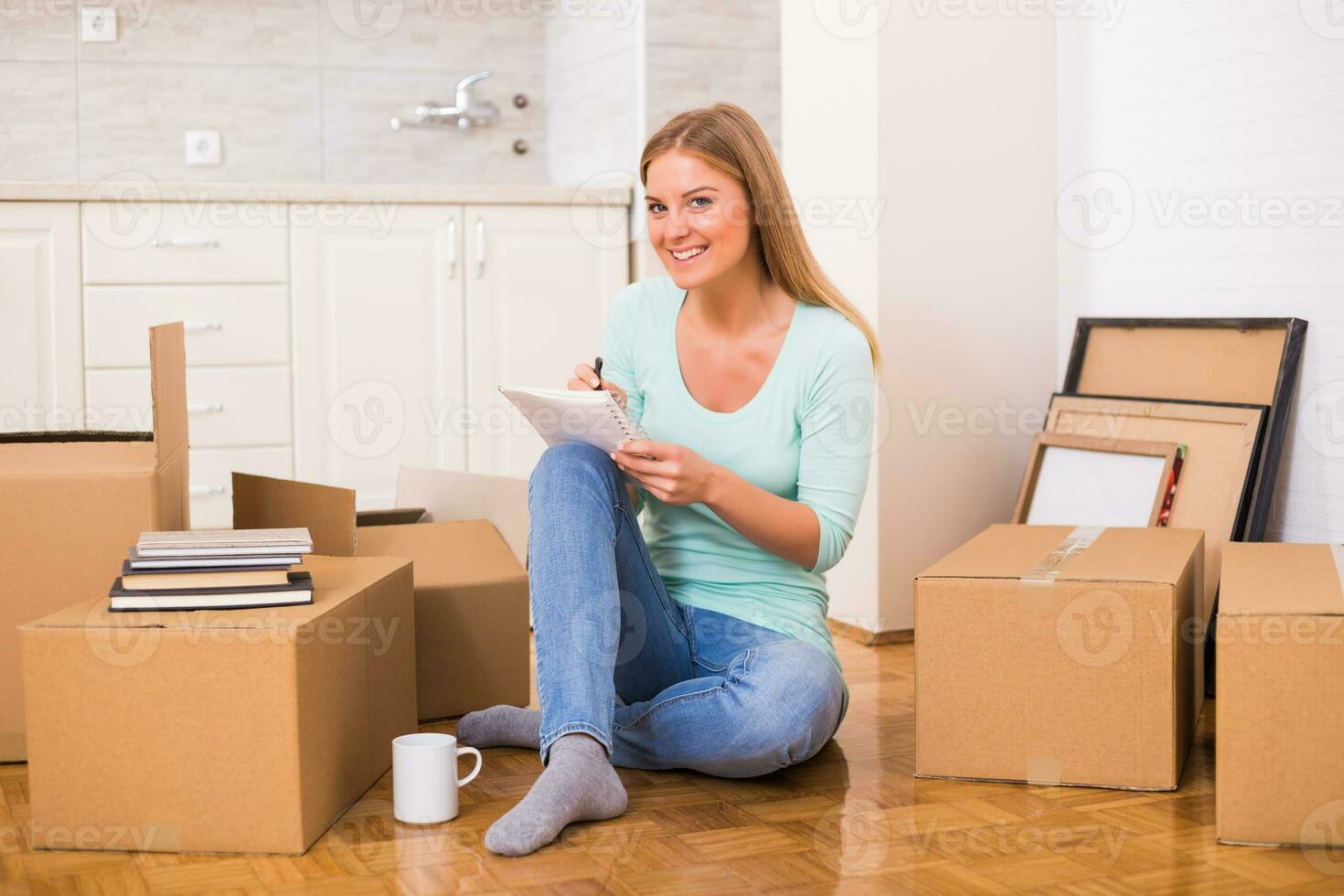 Beautiful woman writing in notebook while moving in new home. photo