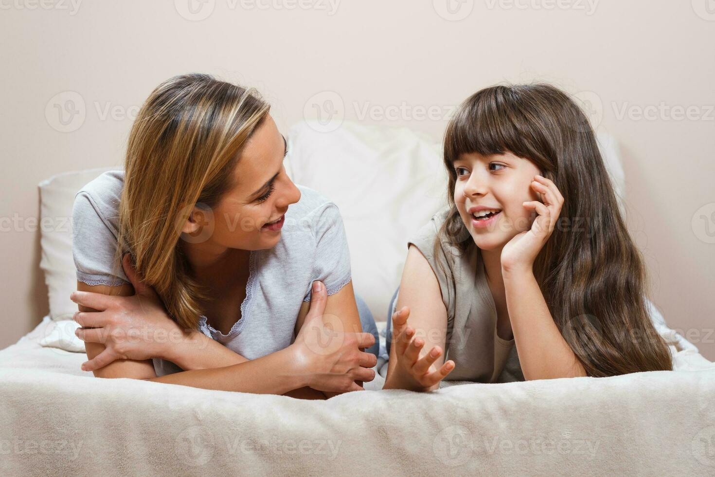 contento madre y hija hablando en cama foto