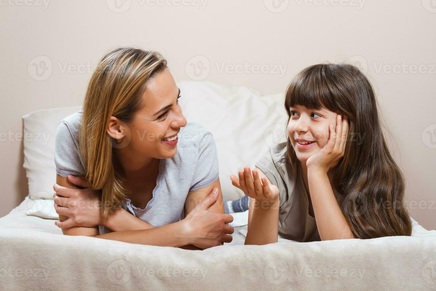 contento madre y hija hablando en cama foto