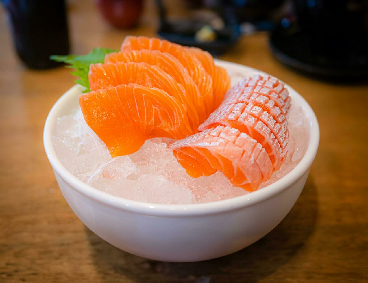 Salmon sashimi in a white ceramic cup Keep it cool and fresh with ice. Raw fish or sashimi is a popular dish of famous Japanese restaurants. photo