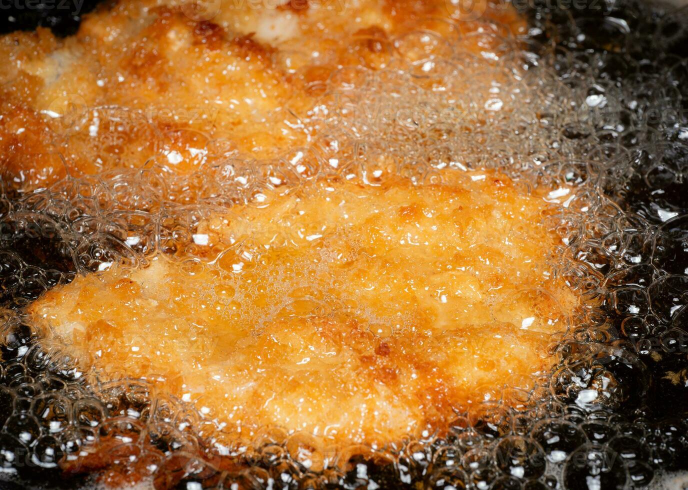 Breaded Fried Chicken. Foods fried in boiling oil in a Chinese wok. Cooking by frying in hot oil. Bubbles appear from frying photo