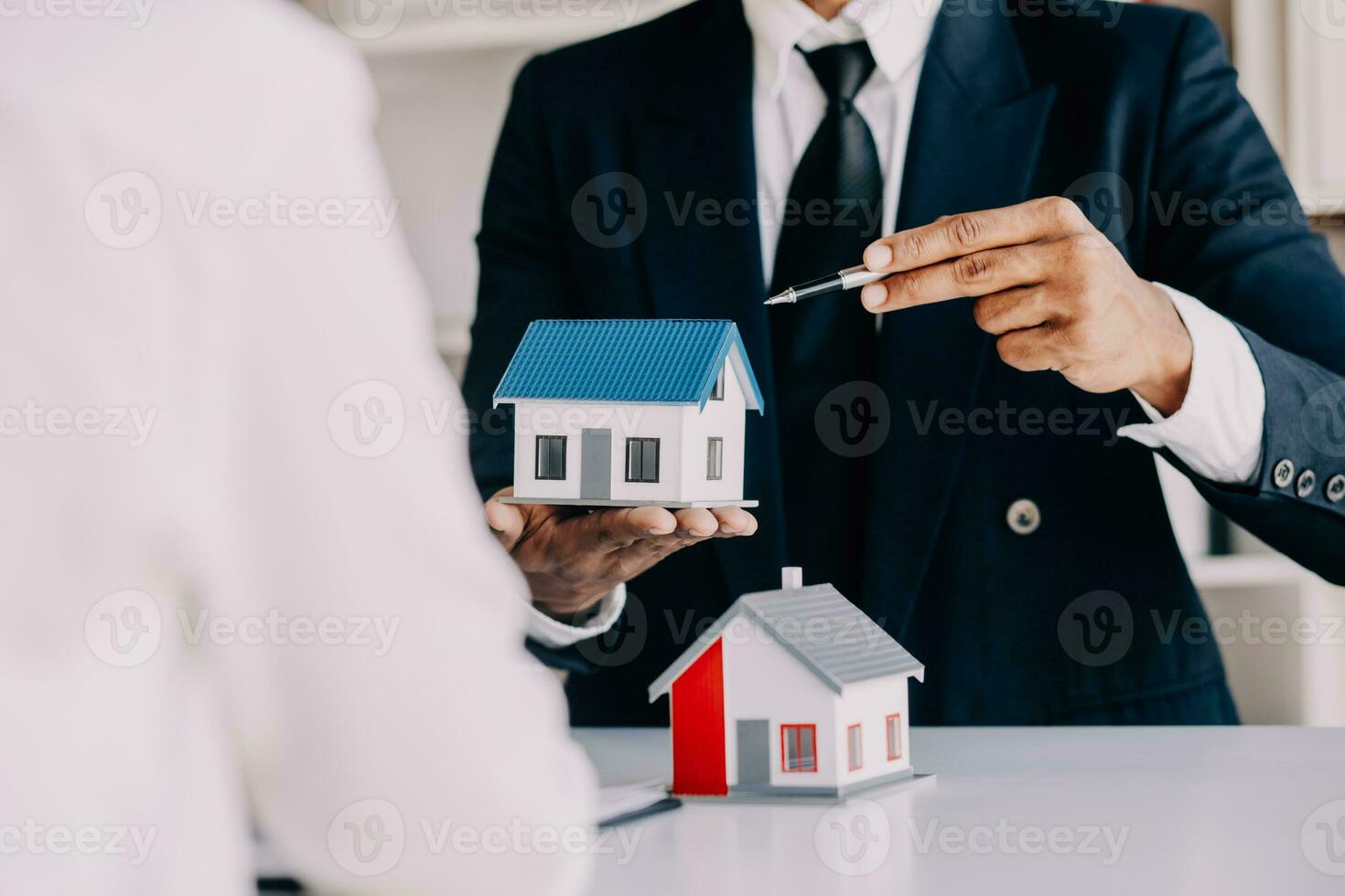 A couple is approaching a housing project to buy, and they are discussing details and advice with a salesperson in a housing project. Real estate trading ideas with couples. photo