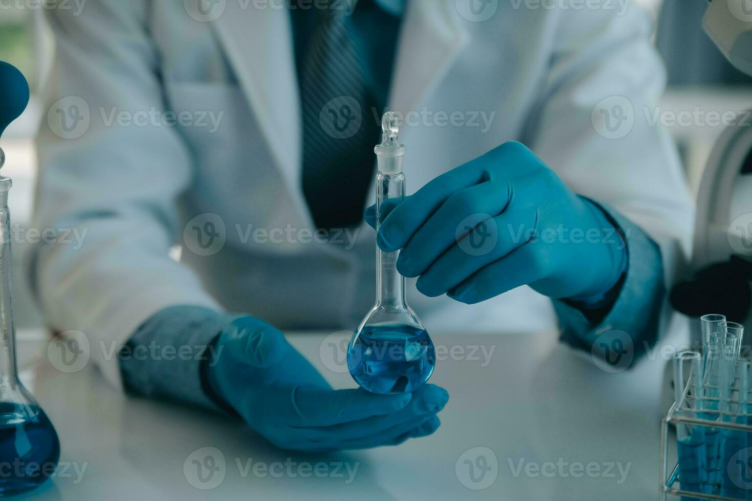 biochemical research scientist team working with microscope for coronavirus vaccine development in pharmaceutical research labolatory, selective focus photo